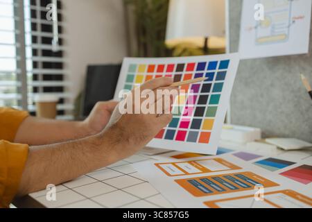 A web designer is using his idea to create a digital product design project that will meet the needs of users in terms of both appearance and feel whe Stock Photo