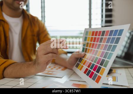 A web designer is using his idea to create a digital product design project that will meet the needs of users in terms of both appearance and feel whe Stock Photo