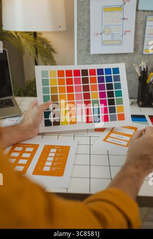 A web designer is using his idea to create a digital product design project that will meet the needs of users in terms of both appearance and feel whe Stock Photo