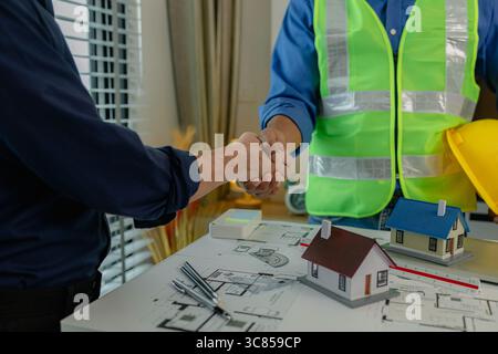 engineer and architect are shaking hands to celebrate because they just finished big construction project, two engineers do handshake after the meetin Stock Photo