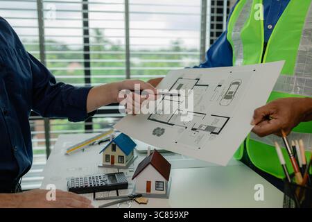 an engineer is in the office with his assistant, they are examining every detail in the blueprint, two architects are exchanging their idea to each ot Stock Photo