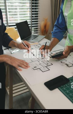 an engineer is in the office with his assistant, they are examining every detail in the blueprint, two architects are exchanging their idea to each ot Stock Photo