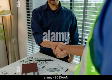 engineer and architect are shaking hands to celebrate because they just finished big construction project, two engineers do handshake after the meetin Stock Photo