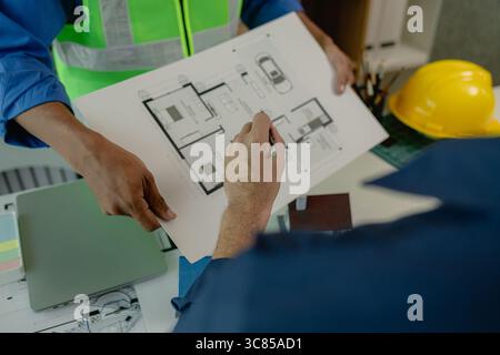 an engineer is in the office with his assistant, they are examining every detail in the blueprint, two architects are exchanging their idea to each ot Stock Photo