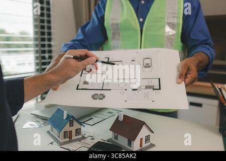 an engineer is in the office with his assistant, they are examining every detail in the blueprint, two architects are exchanging their idea to each ot Stock Photo