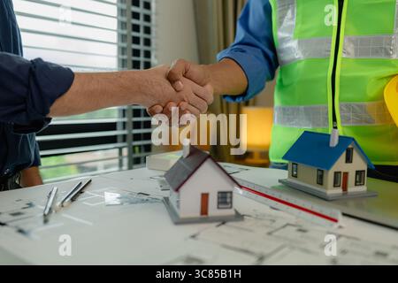engineer and architect are shaking hands to celebrate because they just finished big construction project, two engineers do handshake after the meetin Stock Photo