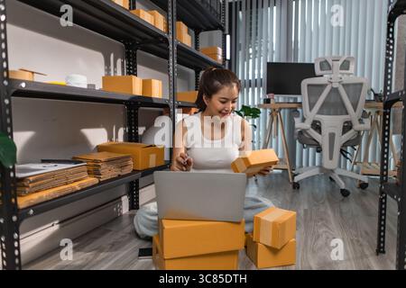 a female employee is checking parcel boxes in a warehouse, a warehouse manager is counting parcel boxes on shelves, a small online business owner is i Stock Photo
