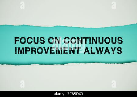 Focus On Continuous Improvement Always text on blue with white paper torn ripped of horizontal Stock Photo