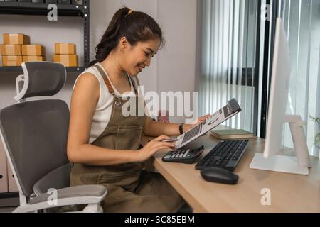 warehouse manager is entering data into computer, an employee is checking shipping addresses for accuracy in the stockroom, a small business owner is Stock Photo