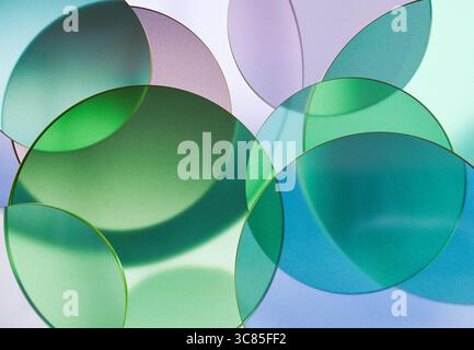 3D rendering of Overlapping Transparent Green and Blue Glass Discs Creating Soft Abstract Patterns on a Light Background Stock Photo