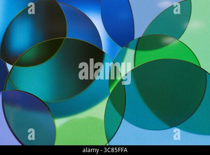 3D rendering of Overlapping Transparent Blue and Green Glass Discs Creating Abstract Patterns with Light and Reflection Effects Stock Photo