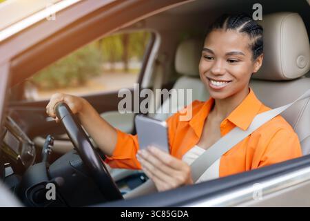 Young black woman checking her smartphone while seated in car Stock Photo