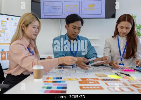 ux, ui, web and mobile app designers are discussing the look and feel of the website or app they are designing including color schemes and layouts to Stock Photo