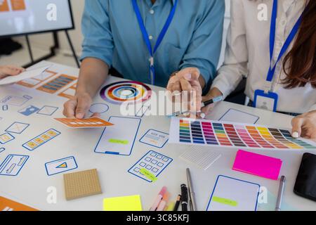 ux, ui, web and mobile app designers are discussing the look and feel of the website or app they are designing including color schemes and layouts to Stock Photo