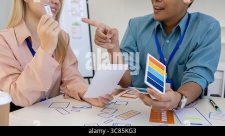 ux, ui, web and mobile app designers are discussing the look and feel of the website or app they are designing including color schemes and layouts to Stock Photo