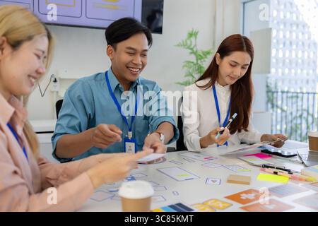 ux, ui, web and mobile app designers are discussing the look and feel of the website or app they are designing including color schemes and layouts to Stock Photo