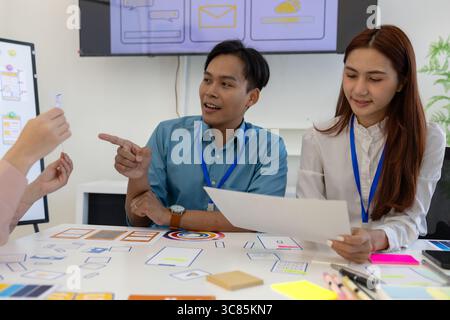 ux, ui, web and mobile app designers are discussing the look and feel of the website or app they are designing including color schemes and layouts to Stock Photo