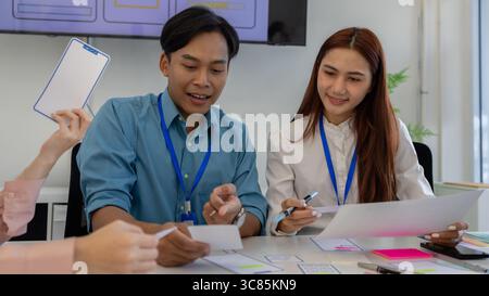 ux, ui, web and mobile app designers are discussing the look and feel of the website or app they are designing including color schemes and layouts to Stock Photo
