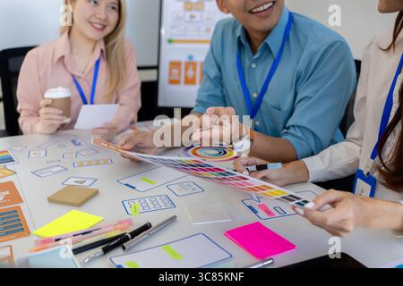 ux, ui, web and mobile app designers are discussing the look and feel of the website or app they are designing including color schemes and layouts to Stock Photo