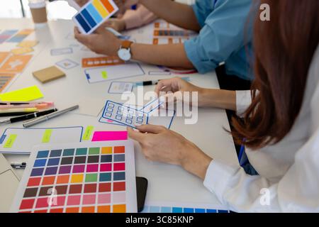 ux, ui, web and mobile app designers are discussing the look and feel of the website or app they are designing including color schemes and layouts to Stock Photo