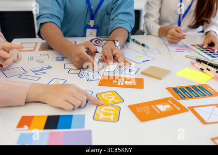 ux, ui, web and mobile app designers are discussing the look and feel of the website or app they are designing including color schemes and layouts to Stock Photo
