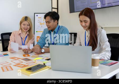 ux, ui, web and mobile app designers are discussing the look and feel of the website or app they are designing including color schemes and layouts to Stock Photo