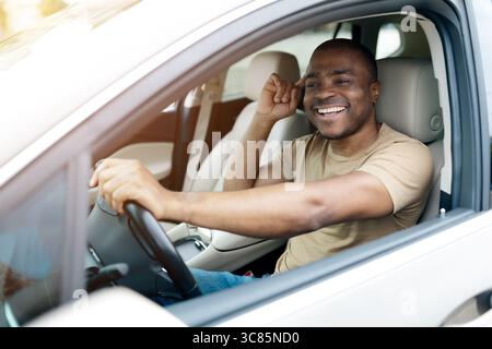 Confident African American man smiling while sitting in drivers seat, Stock Photo