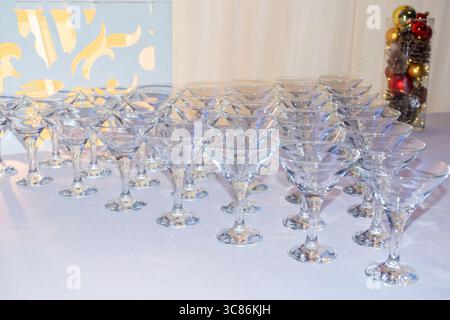 A beautiful display of crystal glasses is neatly arranged on a table, ready for a festive event. The setting features colorful decorations that enhanc Stock Photo