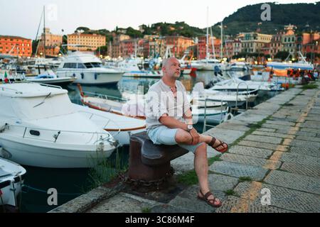 Casual traveler adjusting camera settings on cobblestone street in picturesque village. Stock Photo