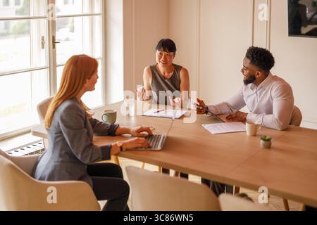 Professionals analyzing reports and collaborating on strategic solutions during meeting in board room Stock Photo