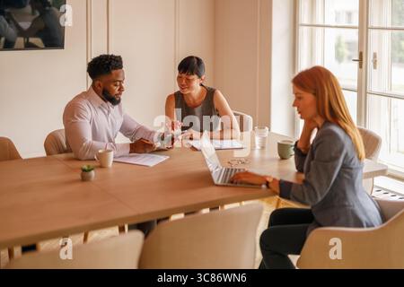 Professionals reviewing data over digital tablet and collaborating on new strategies and ideas in office meeting Stock Photo