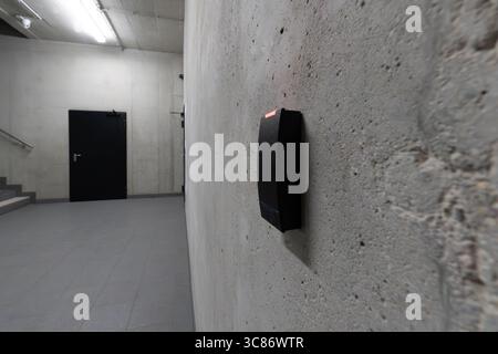Access card reader security concrete stairwell. Modern electronic badge terminal on rough industrial wall near closed door in empty office building Stock Photo
