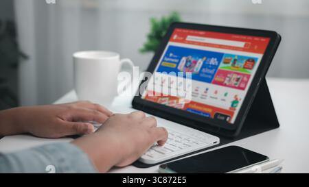 Shopping online concept, Close-up of human hands typing on wireless keyboard while shopping online on tablet screen, e commerce concept, indoor home o Stock Photo