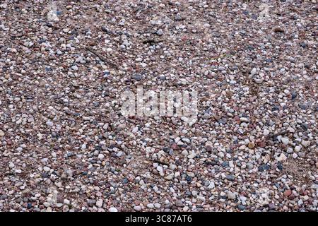A mix of small stones and pebbles creates a vibrant gravel surface in a natural outdoor environment under bright daylight. Stock Photo