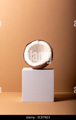 Cracked coconut on white stand. Minimal concept. Stock Photo