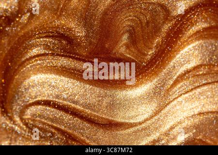 Glowing golden shimmering cosmetic texture of gel or body spray. Background texture for backdrops or mapping. Stock Photo