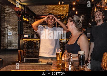 Young male reacting with disappointment after losing a shuffleboard game, holding hands on head in disbelief. Stock Photo