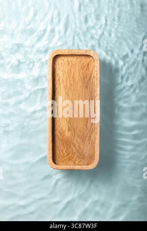 Presentation scene made with wooden pedestal floating in blue ripple water. Top view backdrop. Stock Photo