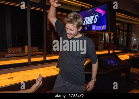 Young male celebrating a bowling strike with a high five, showing excitement and camaraderie during a fun night out at the bowling alley. Stock Photo