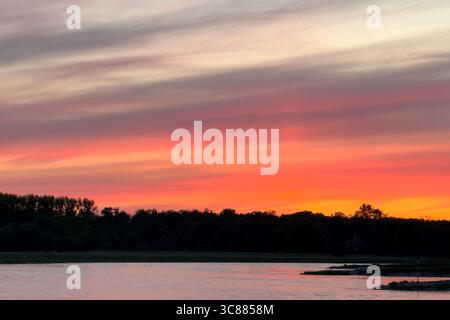 Colorful reddish and purple sunset takes place over Germany's Elbe River. Stock Photo