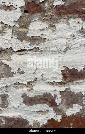 White paint peeling off weathered red brick on a medieval buidling creates an interesting textured background plate. Stock Photo