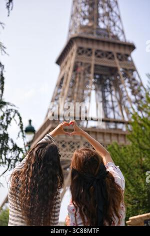 Two women making heart shape with hands near Eiffel Tower Paris Stock Photo