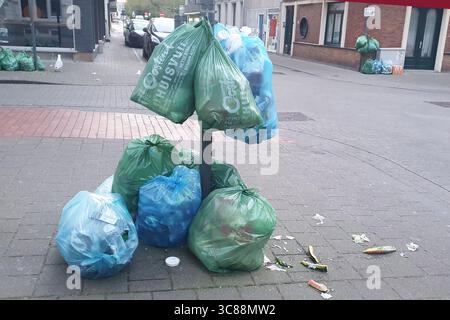 Plastic bags full of trash can on the street of the city. Green and blue waste sacks. Stock Photo