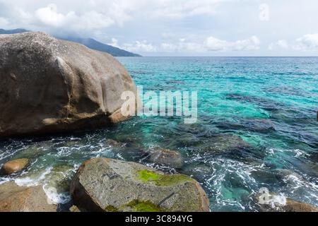 Vivid coastal scene featuring clear turquoise seawater, rugged rocky formations, and a serene atmosphere. Ideal for relaxation, nature, and travel con Stock Photo