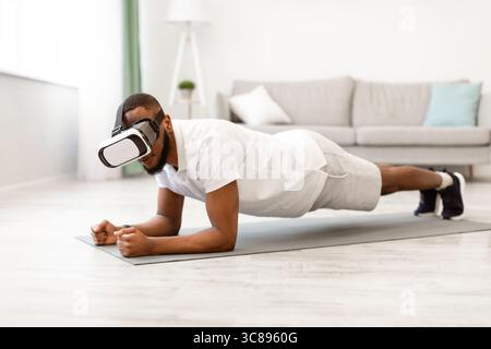 Black Man Wearing VR Glasses Standing In Plank At Home Stock Photo