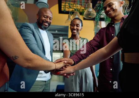 Diverse group of business people stacking hands for teamwork in office Stock Photo