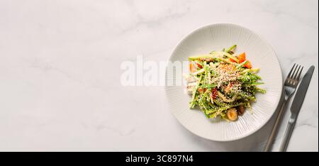 Delicious pork meat salad with cucumber in asian style with amaranth popcorn or popped amaranth replaceable sesame on white marble background. Top vie Stock Photo