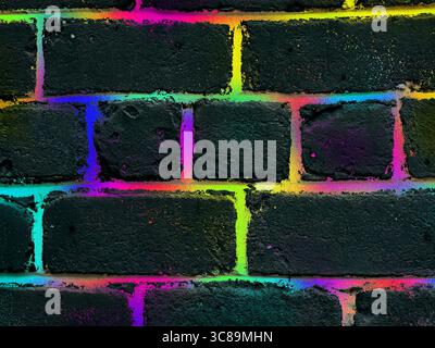 Neon colors light up a textured brick wall, creating a vibrant, modern abstract design.A dark brick wall with vibrant neon colours illuminating the te Stock Photo
