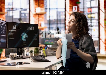 Woman at agency office using financial application UI on PC screen showing company revenue and expenses. Female expert working from apartment doing annual profits review using computer. Stock Photo