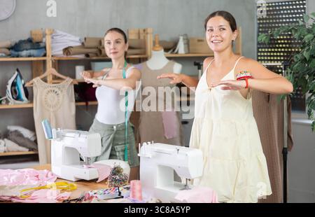 Female dressmakers doing a warm-up in the workshop in summer Stock Photo